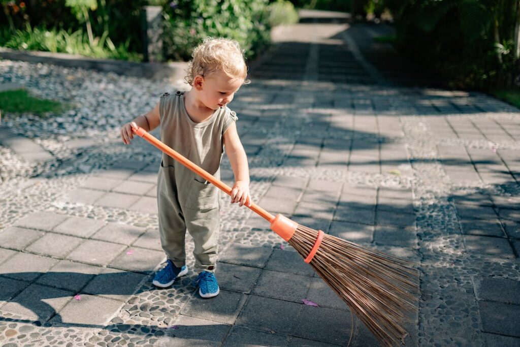 toddler sweeping in garden